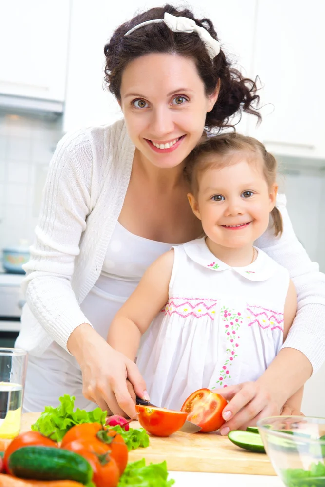 Lina Vexley - Mother and daughter cutting fresh vegetables together in a kitchen.